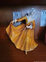 Front view of the Royal Doulton Kirsty figurine showing the flowing yellow dress and raised arm holding the skirt.