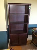 Front view of the dark wood bookshelf with open shelving and closed cabinet below.