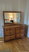 Front view of the Vilas Canada wooden dresser with six drawers and large mirror mounted on the back.