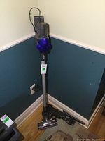 Upright cordless vacuum with wand and motorized floor head standing in corner