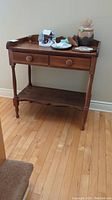 Front view of wooden hall table with two drawers and decorative items on top.