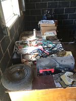 View of workbench with assorted items including mailbox, wheelbarrow tire, greaser, cords, and small tools scattered