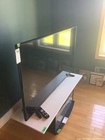 Side-angle view of the TV on a table showing remote and pedestal stands