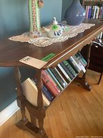 View of the full table showing bookshelf with books underneath and several decorative items on top.