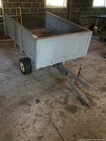 Front corner view of trailer showing steel frame, side panels, and plywood floor.