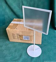 Three adjustable white rectangular sign holders with clear protective cover, each on a circular base, shown with their original cardboard box.
