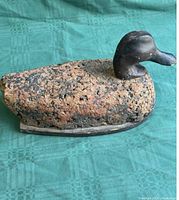 Antique duck decoy with a textured cork body and dark wooden carved head viewed from the right side showing the shape and finish of the decoy.