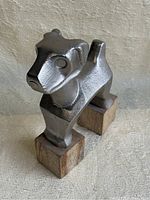 Front view showing stylized dog head, silver aluminum finish, and wooden block feet