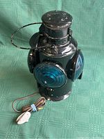 Oblique front view showing two colored lenses and metal body with attached cord and switch.