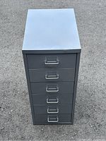 Top view of steel multi drawer cabinet showing flat top surface with slight dents and six drawer fronts with metal handles and label holders.
