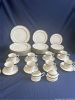 Full set arranged on blue backdrop showing plates, cups, saucers, creamer and sugar bowl
