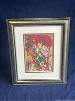Full view of framed original abstract oil painting by LeeGold showing colors red, green, purple, yellow, white and the silver-black frame.