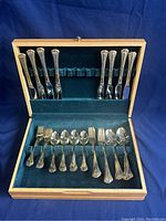 Full set of gold plated flatware in wooden case with velvet lining, showing all items arranged in compartments.
