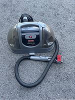 Front view of the Rubbermaid Commercial XTRA-LIFT PDC deep cleaner showing the handle, power button, and connected hose with brush attachment laid out in front.