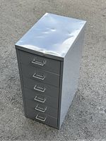 Steel 6 drawer metal storage cabinet showing dented top surface and six metal pull handles on drawers.