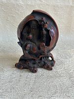 Front view of the dark resin figurine of Shou Lao inside a peach, showing detailed carving and textured base.