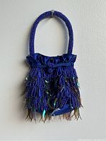 Front view of blue handmade women's handbag with beaded handle and sequin fringe embellishments.