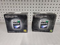 Front view of two AMD Phenom II Black Edition Multi-Core Processor retail boxes stacked side by side showing front packaging.