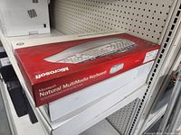 Photo of three boxes of Microsoft multimedia keyboards stacked on a shelf, the top box showing the front side with product image and logo.