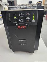 Front view showing APC branding, Smart-UPS 1000 model label, LED indicators, and control buttons on the UPS unit.