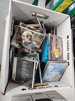 View from above showing a box full of assorted music CDs in jewel cases with visible covers
