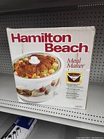 Front of box showing Hamilton Beach Meal Maker slow cooker with 7-quart capacity and image of cooked roast with vegetables inside cooker.