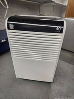 Front view of Kenmore dehumidifier showing black top panel and white vented front with 50 pints marking.