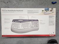 Top of the box showing keyboard with multimedia keys and ergonomic split key design, and feature descriptions.