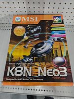 Photo of the MSI K8N Neo3 motherboard retail box with the front showing branding and features. The box is sealed in plastic.
