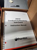 Instruction manual titled '200CR Conductivity/Resistivity Instrument Instruction Manual' by Thornton seen inside a box.