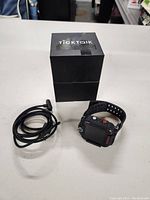 TickTalk 4 smartwatch, charging cable, and original box on a white surface.