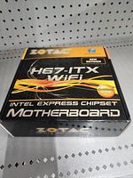 Zotac H67-ITX WiFi motherboard box with Intel Express Chipset branding, black and orange design, new revision label.
