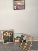 Overview of all framed artworks and easel stand placed near a wall.