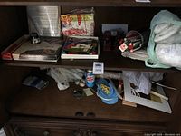 View of shelves displaying knitting supplies, yarn skeins, packaged items, and small miscellaneous craft materials.