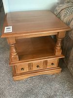Maple end table with three small drawers at the base and open shelf above, turned wooden support columns.