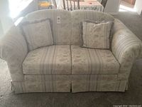 Front view of the loveseat showing two cushions and two floral decorative pillows