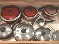 Overview of assorted pots and pans showing red Wearever pots and stainless steel cookware