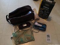 Wide view of the vintage Racine electric clippers, brown zippered grooming pouch, green translucent pouch, Breather training device in plastic case, and Conair Ultimate Shave Kit boxed shaver.