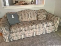 Full view of the patterned sofa bed with cushions on a carpeted floor and part of the room visible.