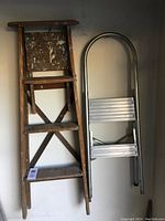 Photo showing both the wooden step ladder with heavy paint marks and the aluminum step ladder side by side.
