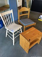 Two vintage chairs and one shoe bench in natural and white wood finishes taken in storage/garage environment.