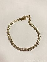 Bracelet coiled on white surface showing full length and link pattern