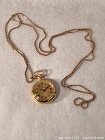 Top‐down view of full 26" chain laid on fabric showing chain and watch front face