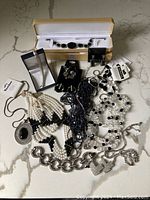Photo of entire lot showing various black and white costume necklaces, bracelets, earrings in different sizes and styles.