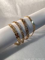 Four bracelets displayed on white roll showing link styles