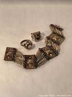 Photo showing the two rings and one bracelet together, highlighting the shape, stones, and linked bracelet design.