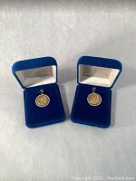 Two pendants displayed in open blue velvet presentation boxes