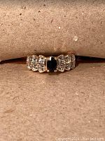 Front view showing oval dark blue stone center and diamond accents