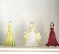 Front view of all three Royal Doulton January figurines together on shelf.