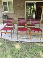 Front view of six teak and red vinyl chairs arranged in two rows on stone patio